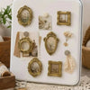 A white tray displaying a set of vintage gold-framed resin mini photo frames for crafting and display.