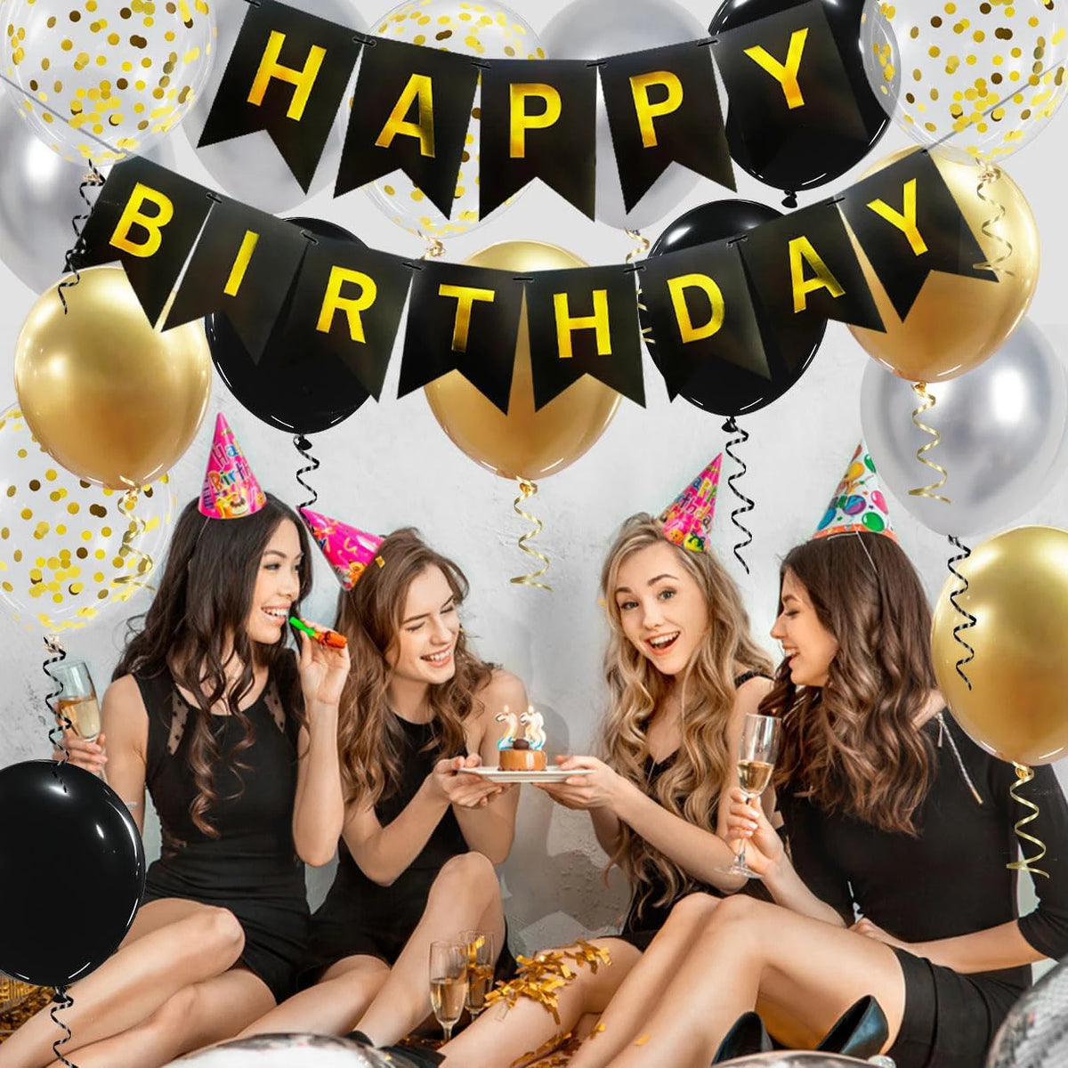 Group of five young women celebrating a birthday with black and gold banner decorations and balloons