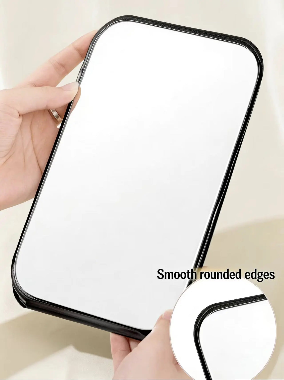 A hand holds a white foldable vanity mirror with smooth rounded edges, showing its design.