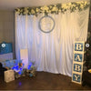 A white draped curtain backdrop for an event featuring a circular sign that reads Baby Boy