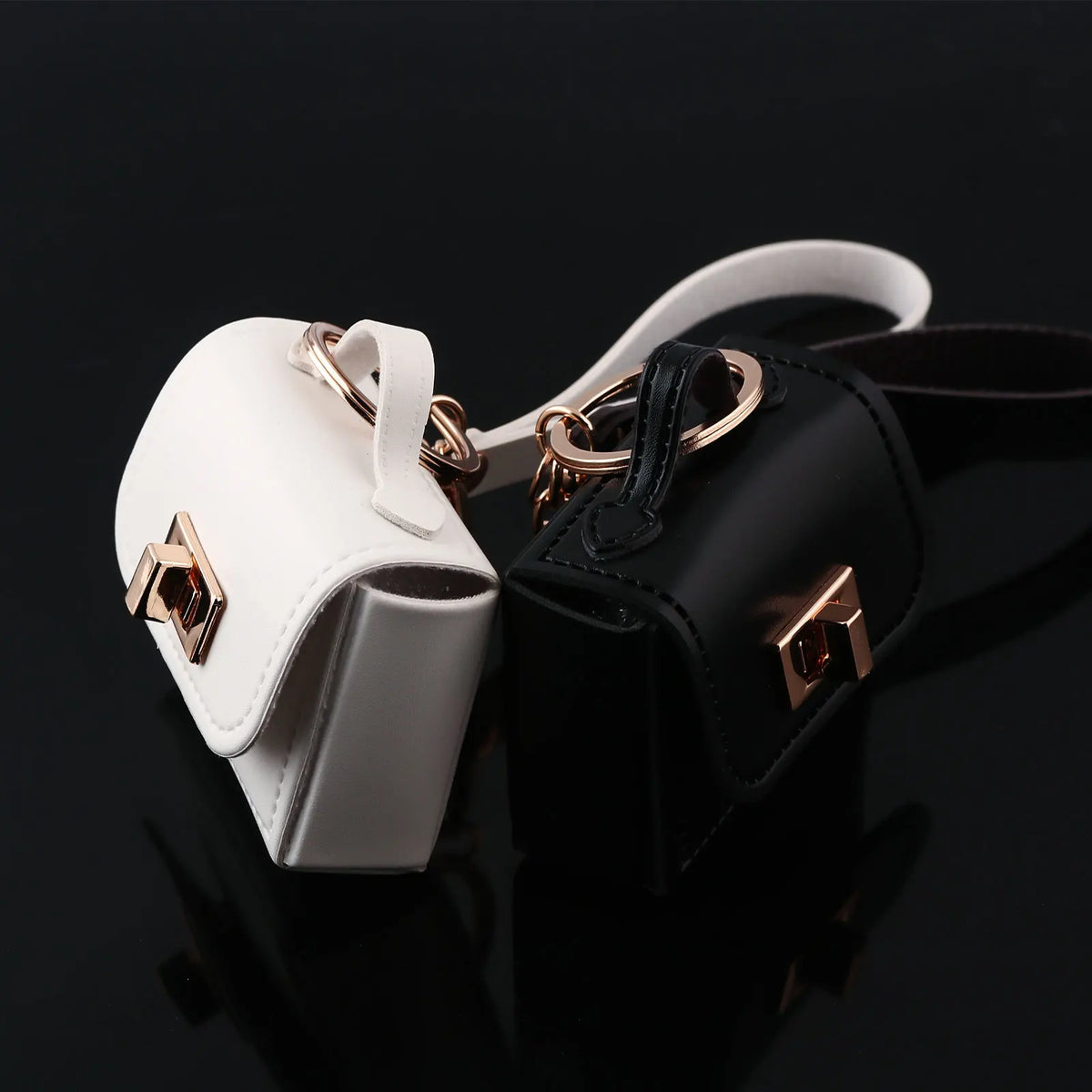 A white and black mini leather openable bag keychain with gold hardware.