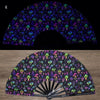A folding fan with a dark background featuring vibrant UV fluorescent floral and nature patterns.