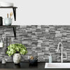 A gray and white stacked stone wall tile background with a modern faucet and sink area.