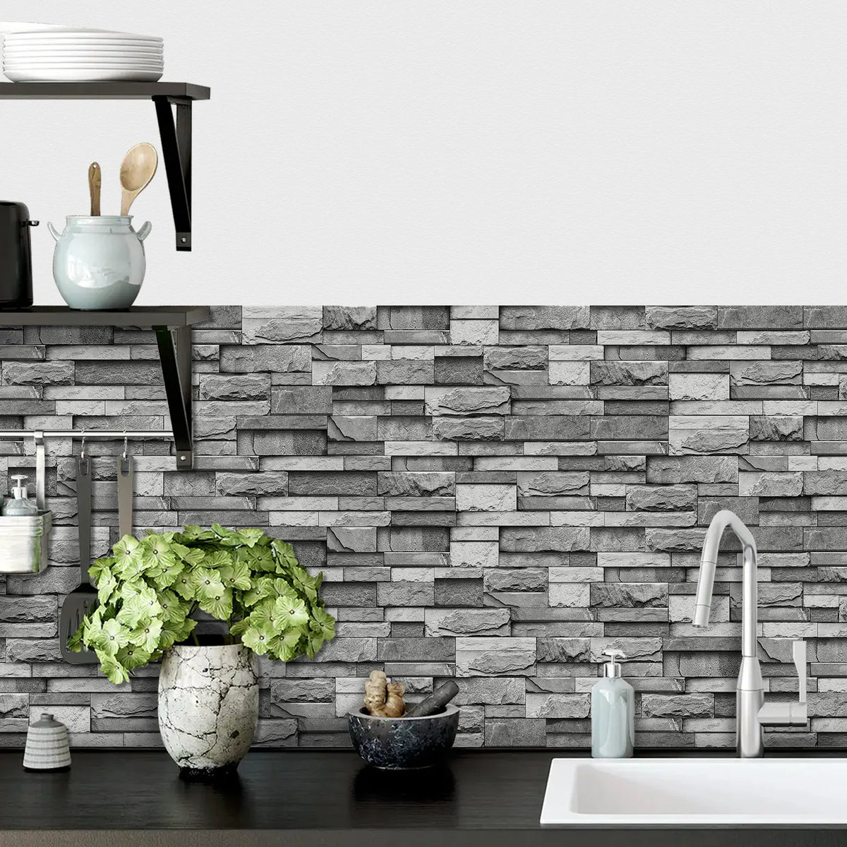 A gray and white stacked stone wall tile background with a modern faucet and sink area.
