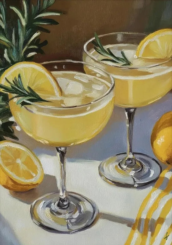 A glass of yellow citrus cocktail garnished with a lemon slice and rosemary on a white surface.