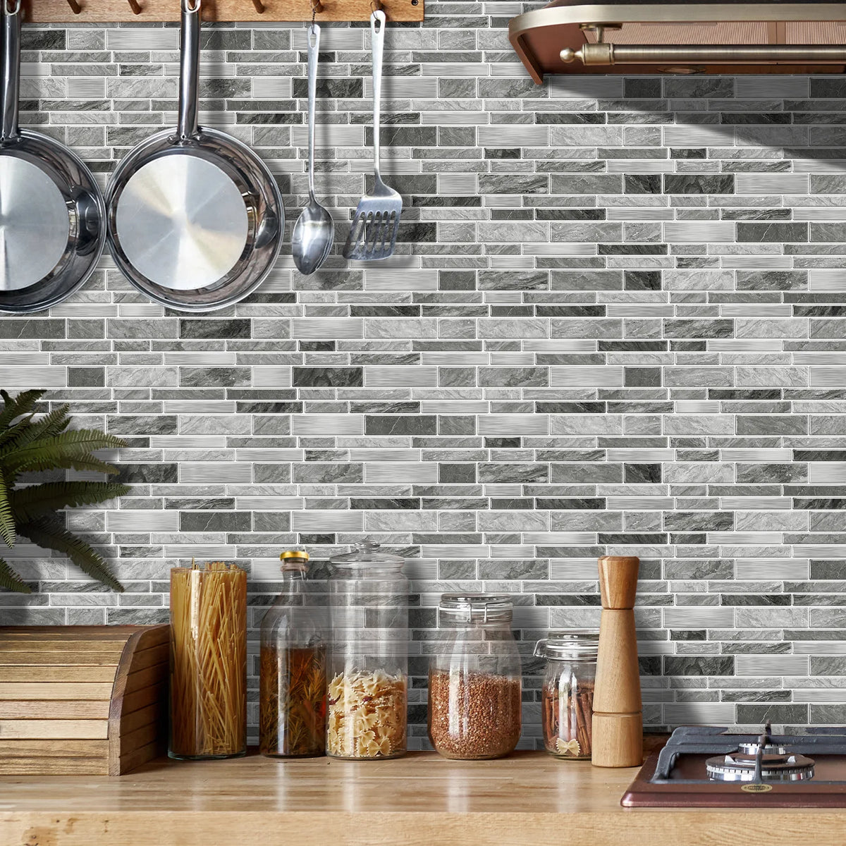 A gray marble tile wall sticker is displayed on a wooden countertop, with kitchen utensils hanging above it.