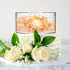 Clear acrylic cake display stands featuring glowing floral arrangements on a white cake.