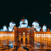 Night view of a mosque with golden domes and minarets reflected on the floor.