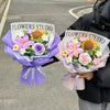 A bouquet of handmade crochet flowers in purple and pink hues is held by a person against an asphalt background.