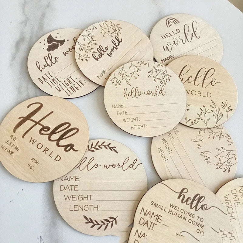 A collection of natural wood baby milestone discs featuring various designs and text like hello world and name