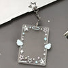 Clear acrylic photocard holder with star and cloud designs attached to a silver keychain.
