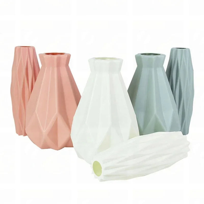 A collection of tall, tapered plastic vases in pink, white, and gray shades.