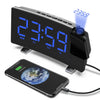 A black projection alarm clock with a large LED display showing 23:59 and an FM radio receiver, connected to a smartphone.