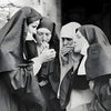 Gravure en noir et blanc de trois religieuses fumant ensemble dans une pénombre.