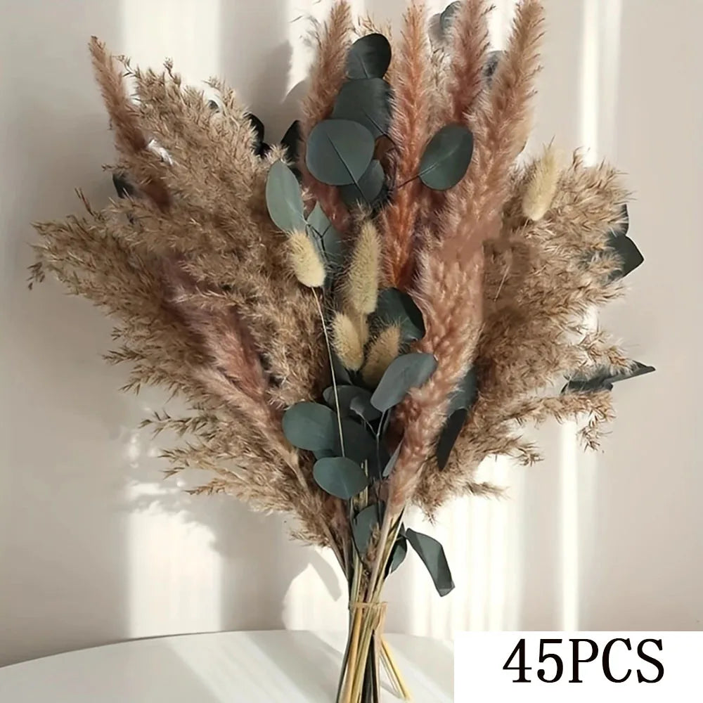 A bouquet of dried pampas grass and eucalyptus leaves in natural beige and dusty rose tones.