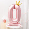 A pink foil number balloon shaped like the digit zero with a gold crown on top.