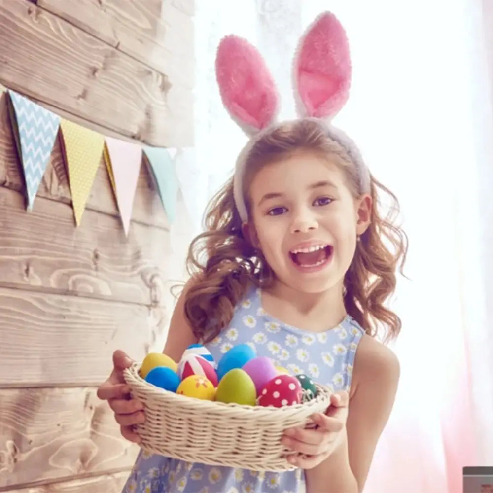 A young girl holding a woven basket filled with colorful Easter eggs and bunny ear headbands.