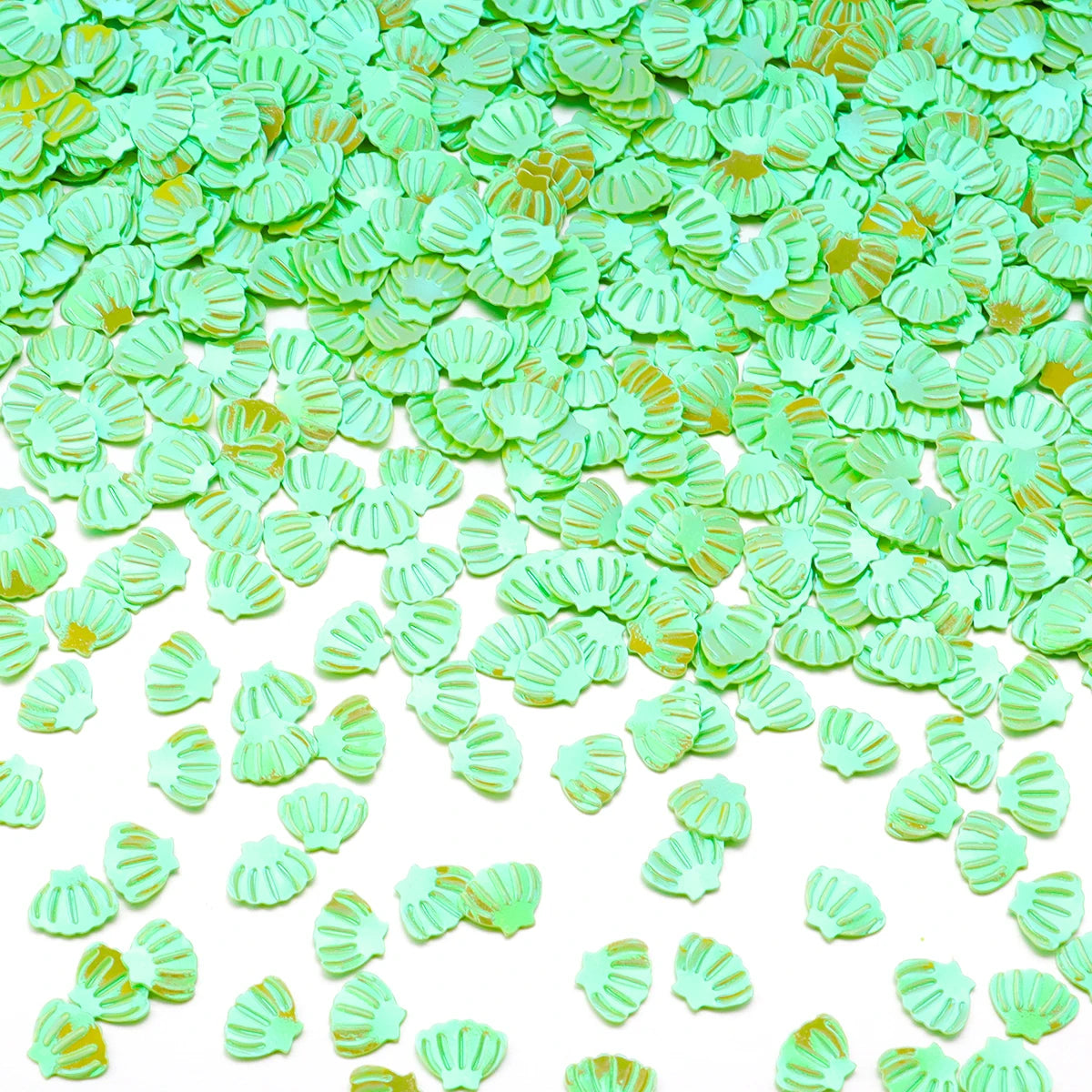Green sea shell PVC sequins scattered on a white background for nail art and craft decoration