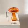 Décor en forme de champignon en verre aux tons orange-ambre, posé sur une surface blanche.