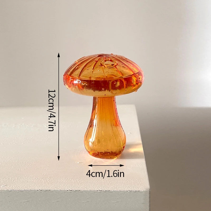 Décor en forme de champignon en verre aux tons orange-ambre, posé sur une surface blanche.