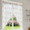 Elegantes Dreieck-Spitzenvorhang mit rosa Blumenmuster, der eine Glastür oder -fenster bedeckt.