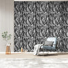 A modern interior featuring a black and white zebra print wall, a gray armchair, and a potted plant.