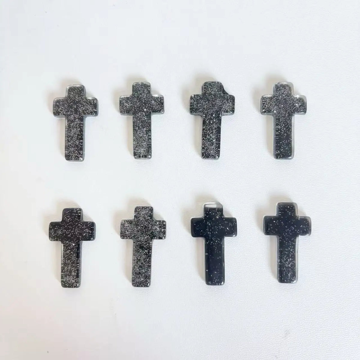 Ein Set aus schwarzen Glitzerkristallkreuz-Dekorationen, angeordnet in zwei Reihen.