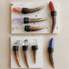 A collection of natural crystal scepter wands featuring various colored crystals like pink, purple, and blue set in wooden ha