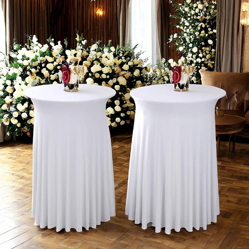 Two white stretch spandex round tablecloths with pleated skirts set up for an elegant event.