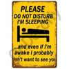 A yellow vintage metal sign with black text warning people not to disturb while sleeping.