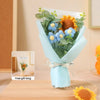A bouquet of handcrafted crochet sunflowers and blue flowers wrapped in light blue paper, presented as a gift.