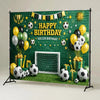 A green soccer field backdrop decorated with balloons, soccer balls, and a banner wishing a happy birthday.