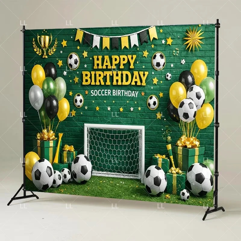 A green soccer field backdrop decorated with balloons, soccer balls, and a banner wishing a happy birthday.