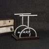 A silver Newton's cradle with balance balls on a dark wooden base.