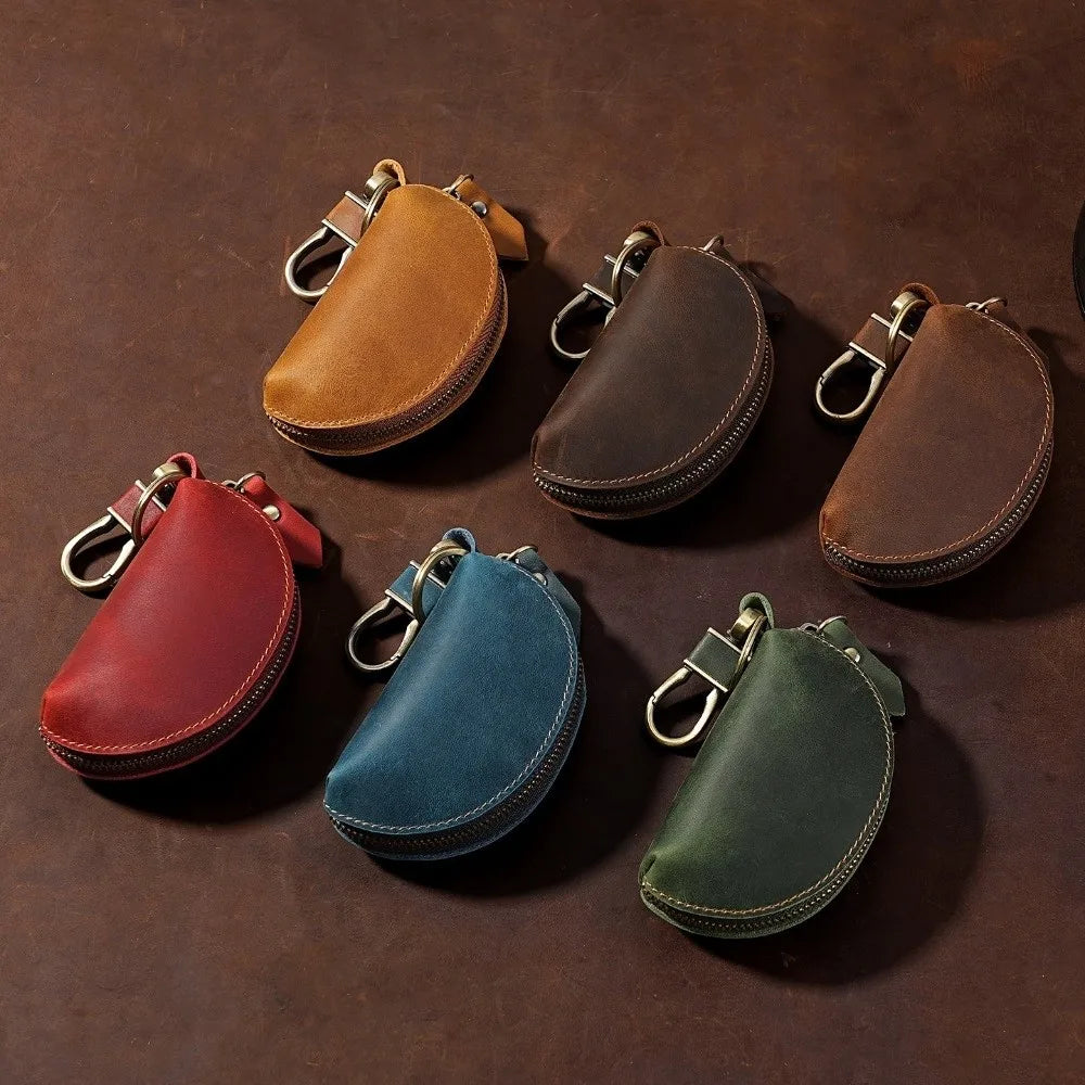 A collection of six brown and green leather key pouches with carabiner clips arranged on a dark surface.