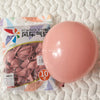 A pink latex balloon is shown next to its packaging for party decorations.