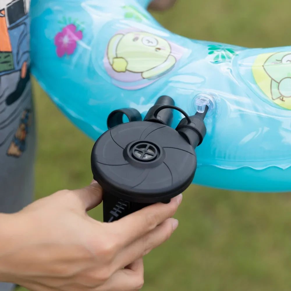 Eine Hand hält eine schwarze portable elektrische Luftpumpe, bereit, ein blaues aufblasbares Objekt aufzupumpen.
