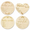Four natural wood baby milestone discs with handwritten text for newborn photography