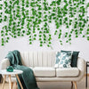 Artificial ivy vine garland draped across a white wall, decorating a light-colored sofa and surrounding area.