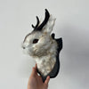 A decorative bunny head made of fur and black material, mounted on a wall.
