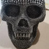 A realistic silver skull resin decorative sculpture covered in small silver beads.