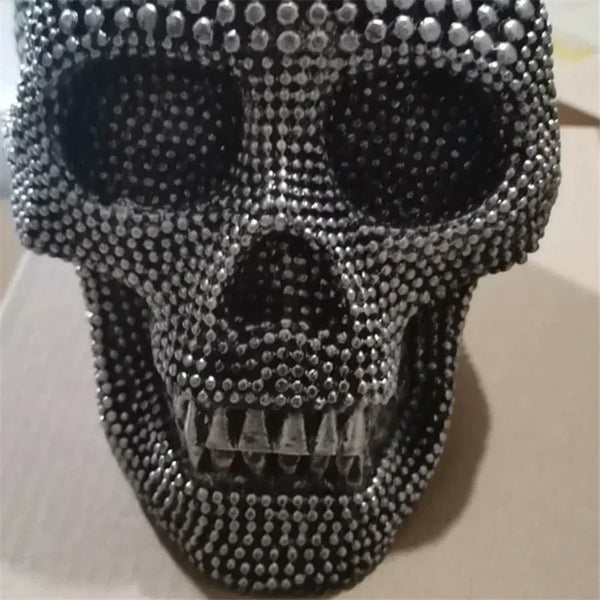 A realistic silver skull resin decorative sculpture covered in small silver beads.