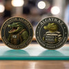 A round collectible coin featuring an alligator head and the text Allatraz and Alcatraz on a dark background.