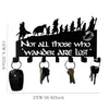 Black decorative metal wall-mounted key holder with seven hooks featuring silhouettes of figures.