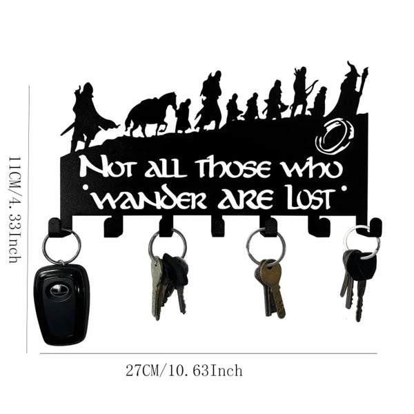 Black decorative metal wall-mounted key holder with seven hooks featuring silhouettes of figures.
