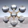 A minimalist molecular sculpture desk decor featuring gold-toned metal connecting several clear glass spheres.