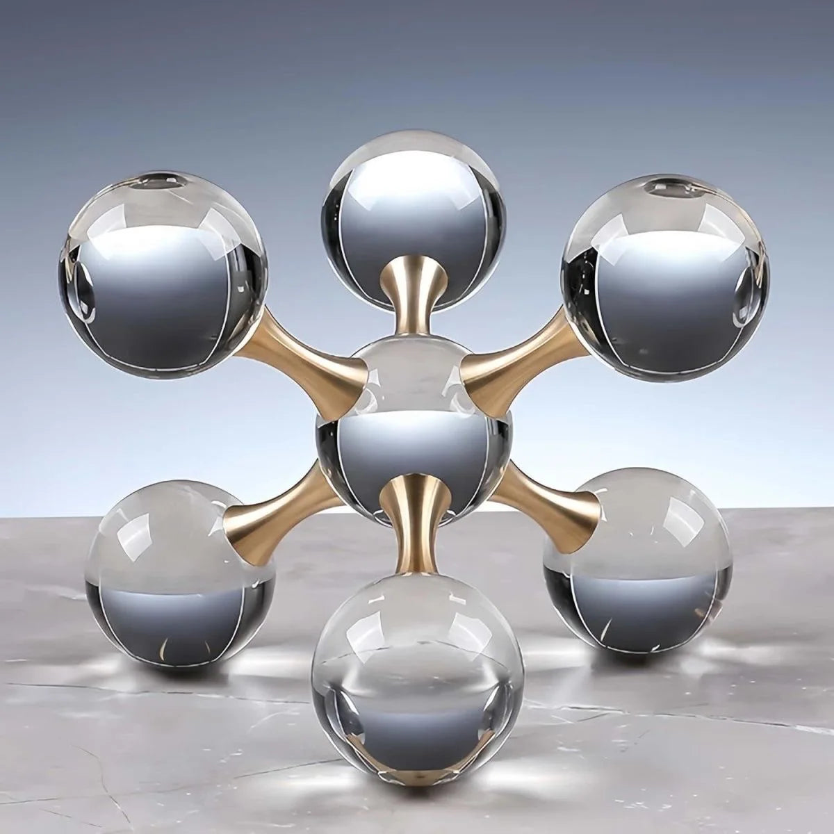 A minimalist molecular sculpture desk decor featuring gold-toned metal connecting several clear glass spheres.