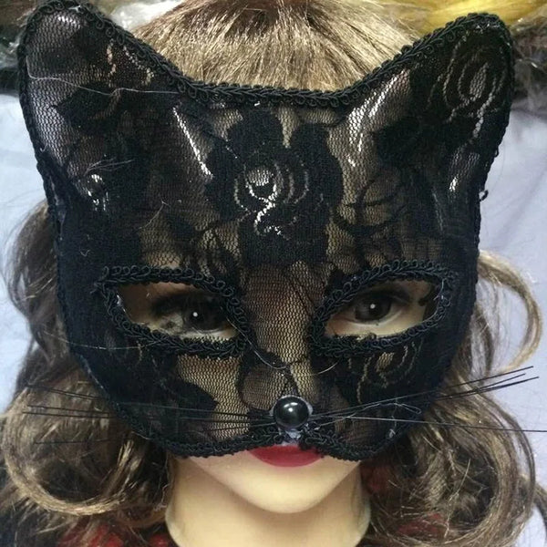A close-up of a black lace half-face mask worn by a person, featuring intricate floral patterns and a small jewel detail.