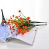 A bundle of bright orange flowers is displayed on an open book next to an Eiffel Tower model.