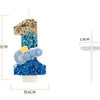 A tall birthday candle shaped like the number one, decorated with blue and gold glitter.